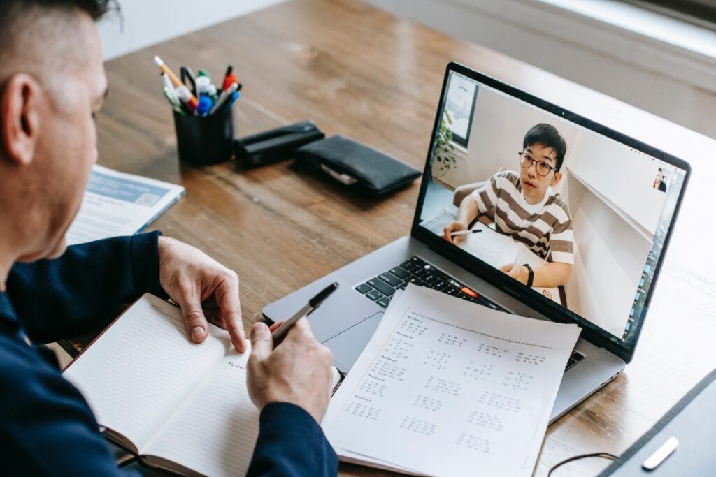 Tutor running an online lesson with a student over a laptop video call